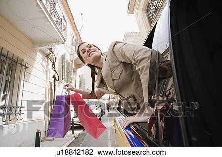 Woman leaning out of car with shopping bags View Large Photo Image Stock Image - Woman leaning out of car with shopping bags. Fotosearch