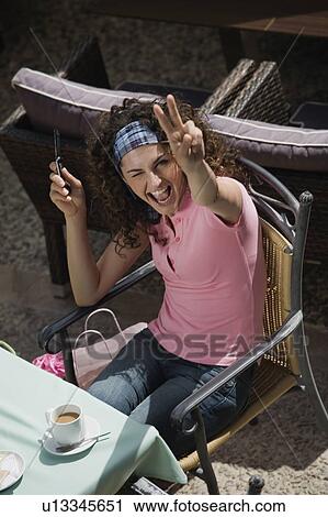 Woman with shopping bags at a cafe making a victory sign View Large Photo Image Stock Image - Woman with shopping bags at a cafe making a victory sign. Fotosearch