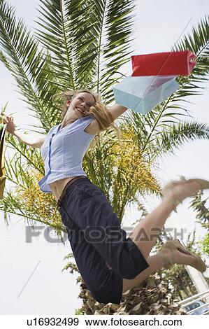 Stock Photo - Woman with shopping bags jumping. Fotosearch