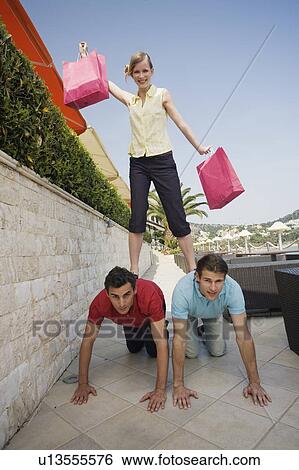 Woman with shopping bags standing on men View Large Photo Image Stock Photograph - Woman with shopping bags standing on men. Fotosearch