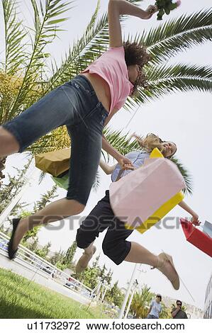 Stock Image - Women with shopping bags jumping. Fotosearch
