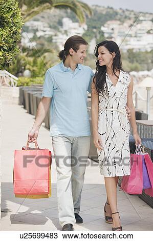 Stock Image - Couple walking with shopping bags. Fotosearch