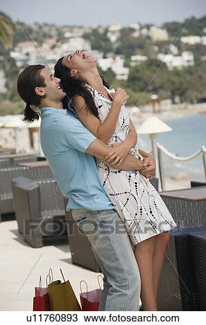 Stock Image - Couple with shopping bags embracing. Fotosearch