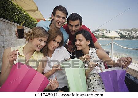 Stock Image - Group of friends with shopping bags posing. Fotosearch