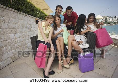 Stock Photo - Group of friends with shopping bags posing. Fotosearch