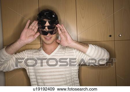 Stock Photo - Man trying on several sunglasses in store. Fotosearch