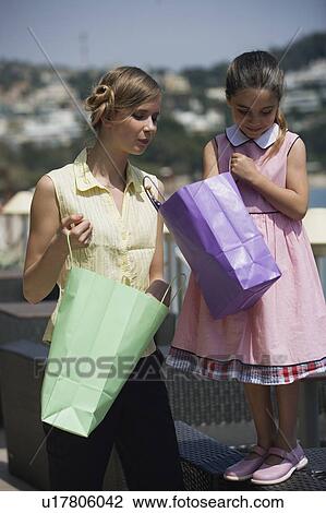 Stock Image - Mother and daughter looking in shopping bags. Fotosearch