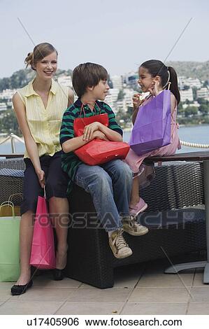 Stock Photograph - Mother and two children with shopping bags. Fotosearch