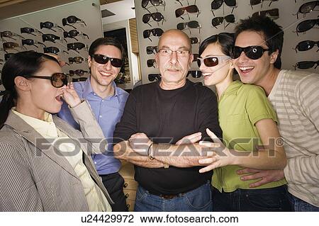 Stock Image - Two couples posing with sunglasses in store with shopkeeper. Fotosearch