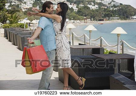 Woman embracing man holding shopping bags View Large Photo Image Stock Image - Woman embracing man holding shopping bags. Fotosearch