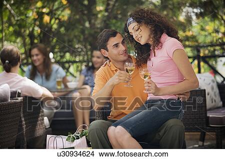 Picture - Woman sitting on man's lap with shopping bags in cafe. Fotosearch