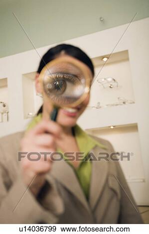 Stock Photo - Woman with magnifying glass on eye. Fotosearch