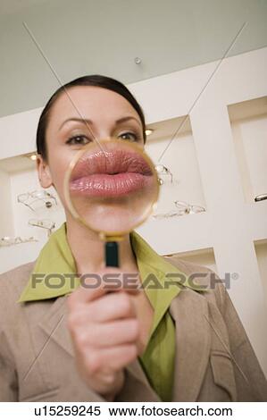 Stock Photography - Woman with magnifying glass on mouth. Fotosearch