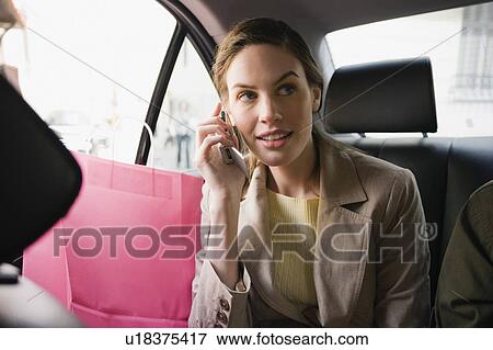 Woman with shopping bags and cell phone in a taxi View Large Photo Image Stock Photo - Woman with shopping bags and cell phone in a taxi. Fotosearch