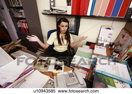 Female office worker at cluttered desk View Large Photo Image Stock Photography - Female office worker at cluttered desk. Fotosearch
