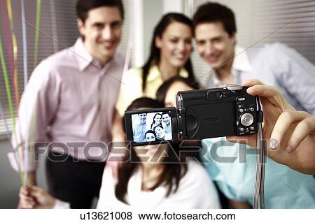Stock Photo - Office colleagues photographing at party. Fotosearch