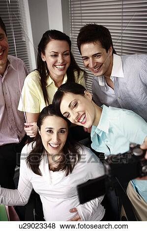 Stock Photo - Office colleagues photographing at party with pregnant colleague. Fotosearch