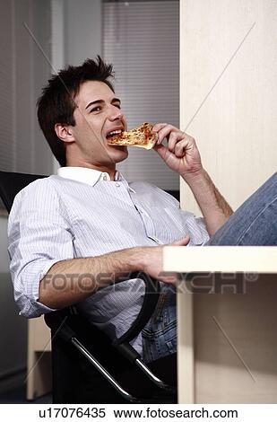 Office worker eating a pizza slice at desk View Large Photo Image Stock Photography - Office worker eating a pizza slice at desk. Fotosearch