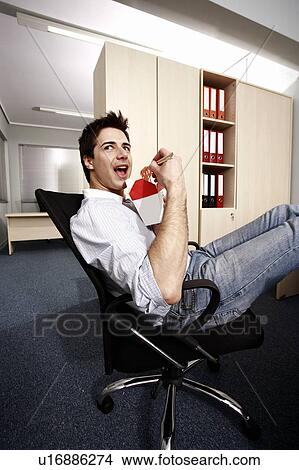 Picture - Office worker eating Chinese food at desk. Fotosearch