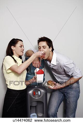 Stock Image - Office worker feeding her colleague. Fotosearch