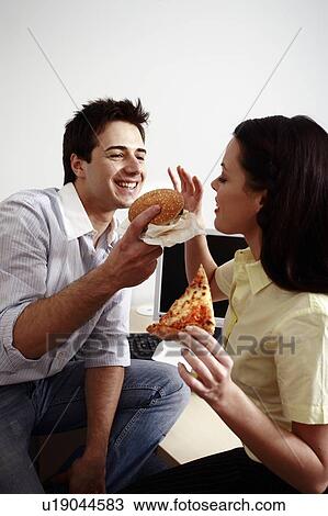 Stock Image - Office worker feeding his colleague at desk. Fotosearch
