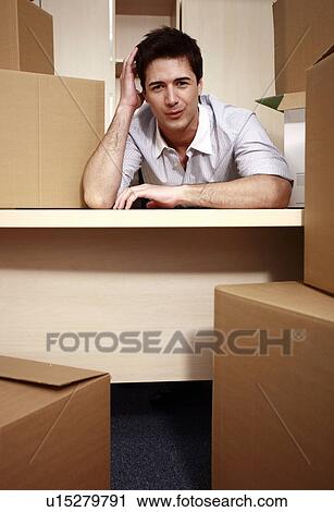 Stock Image - Businessman at desk among boxes. Fotosearch