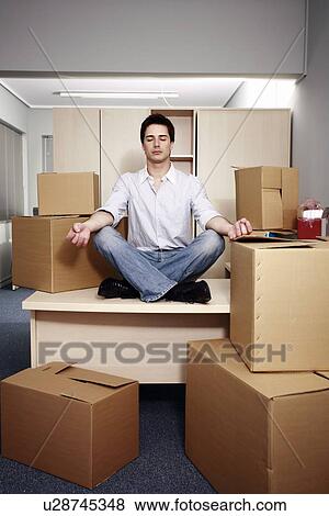 Stock Photo - Businessman on desk among boxes meditating. Fotosearch