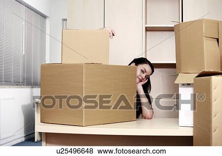 Stock Photo - Businesswoman among boxes at desk. Fotosearch