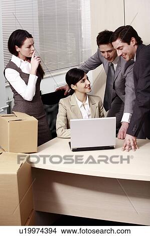 Picture - Four business people at laptop in office. Fotosearch