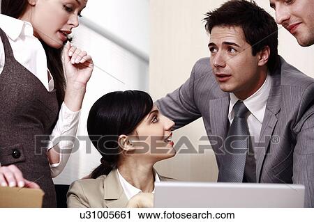 Stock Image - Four business people at laptop in office. Fotosearch