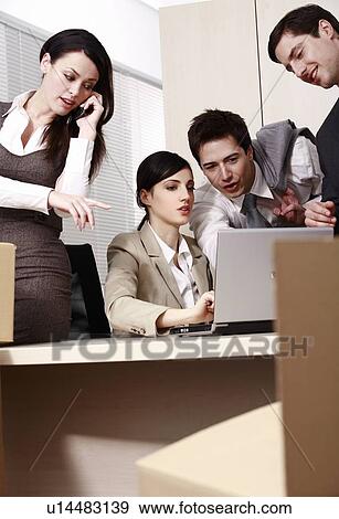 Stock Photo - Four business people at laptop in office. Fotosearch