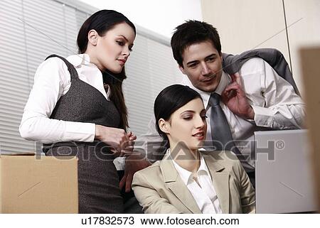 Stock Image - Three business people at laptop in office. Fotosearch