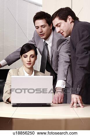 Stock Image - Three business people at laptop in office. Fotosearch