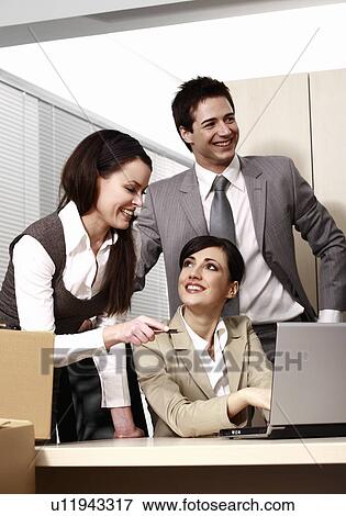 Stock Photo - Three business people at laptop in office. Fotosearch