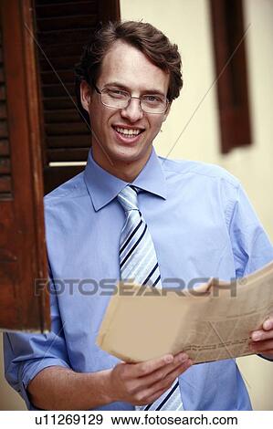 Businessman holding a newspaper View Large Photo Image Stock Photo - Businessman holding a newspaper. Fotosearch