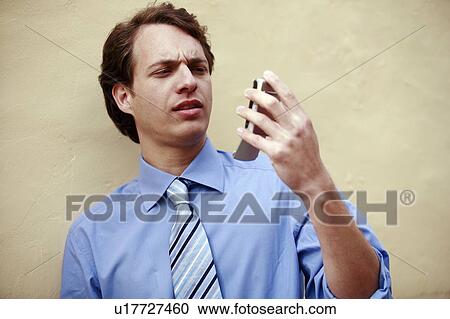 Stock Image - Businessman looking at his cell phone. Fotosearch