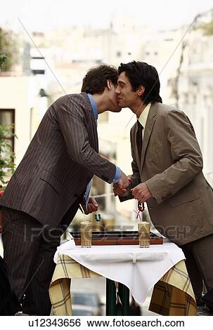Stock Photograph - Businessmen shaking hands and kissing on cheek. Fotosearch