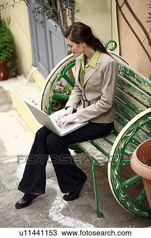 Stock Image - Businesswoman with laptop on a bench. Fotosearch