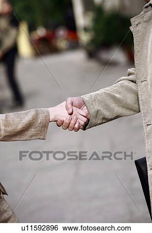 Stock Photograph - Closeup of businessman and woman shaking hands. Fotosearch