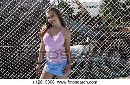 Stock Photo - Female teenager posing at fence. Fotosearch