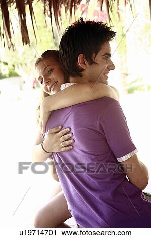 Stock Image - Teenage couple hugging in amusement park. Fotosearch