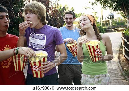 Stock Image - Teenagers hanging out eating popcorn. Fotosearch