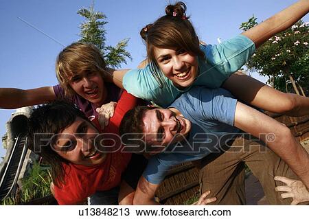 Stock Image - Teenagers playing on piggy back in amusement park. Fotosearch