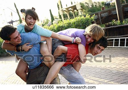 Stock Photograph - Teenagers playing on piggy back in amusement park. Fotosearch