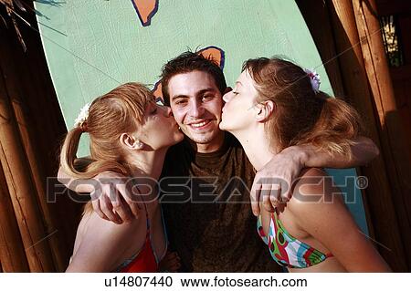 Two female teenagers kissing male teenager on cheek View Large Photo Image Stock Image - Two female teenagers kissing male teenager on cheek. Fotosearch