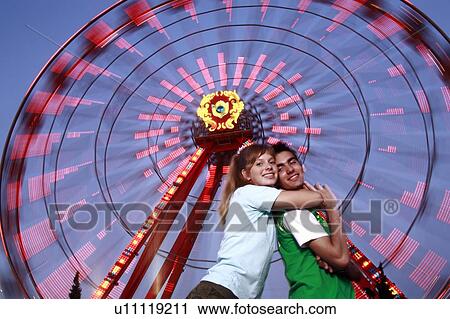 Teenage couple at Ferris wheel in amusement park View Large Photo Image Stock Image - Teenage couple at Ferris wheel in amusement park. Fotosearch