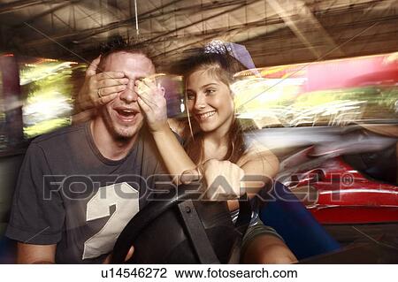 Stock Image - Teenage couple in bumper car in amusement park. Fotosearch