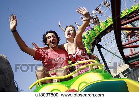 Stock Image - Teenage couple on amusement park ride. Fotosearch