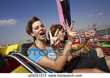 Stock Image - Teenage couple on amusement park ride. Fotosearch