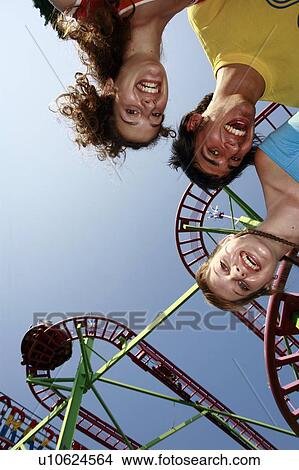 Picture - Teenagers posing at roller coaster at amusement park. Fotosearch
